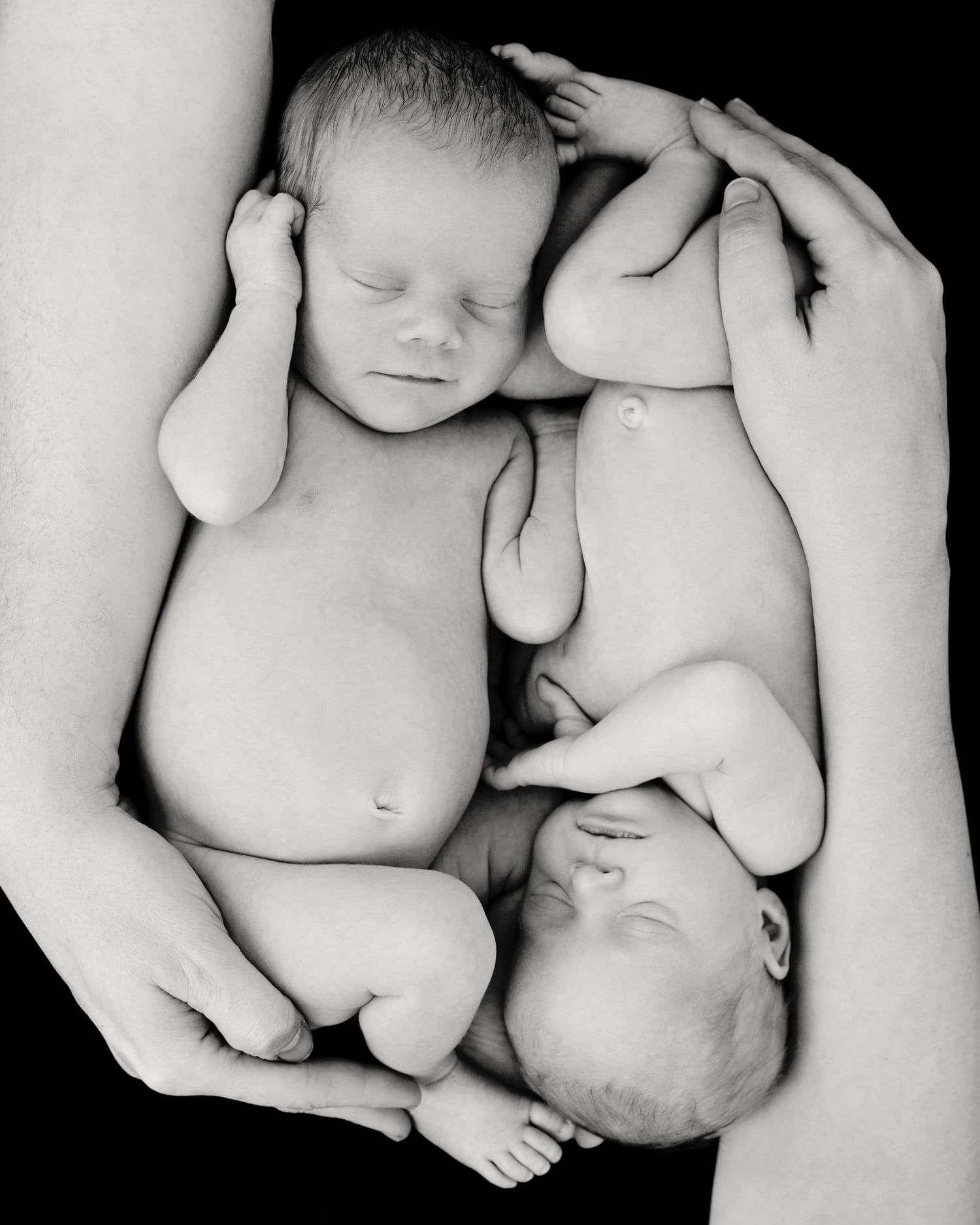 Two newborn babies in a black and white photo.