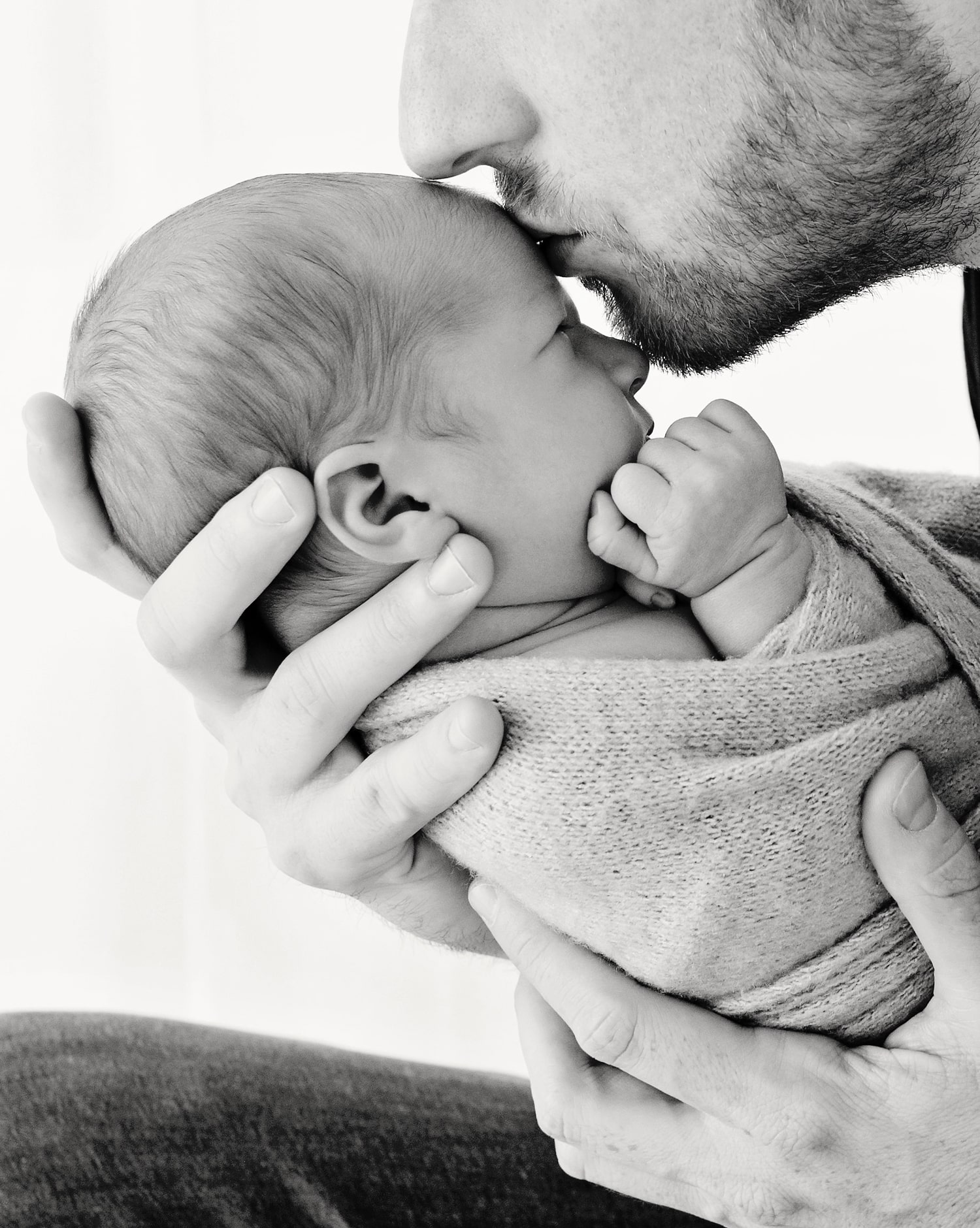 A father kisses his baby's forehead.