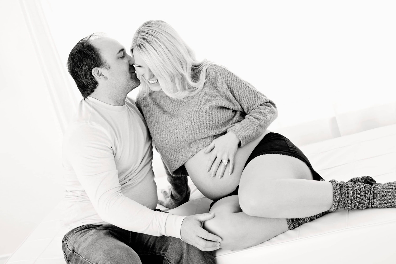 A couple laughs during a maternity photo.
