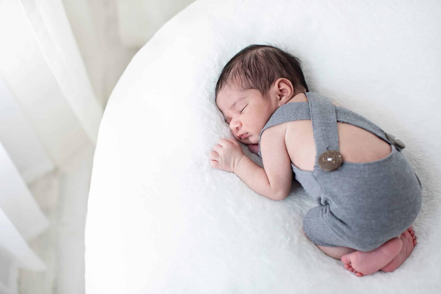 A newborn baby in gray overalls.