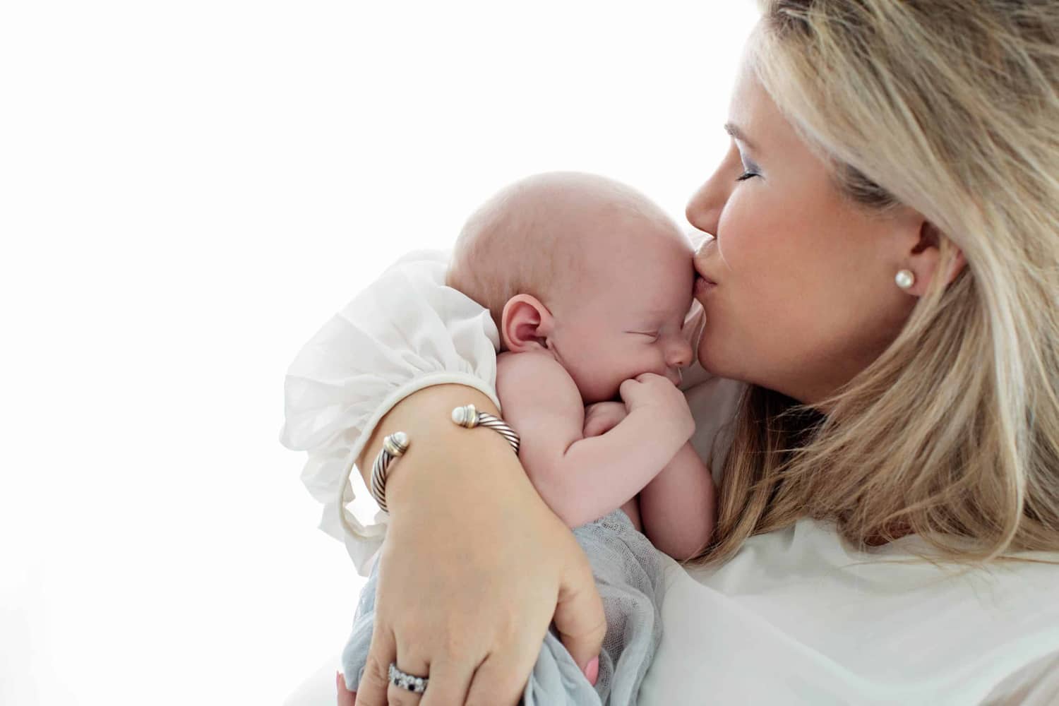 A mom kisses her baby's forehead.