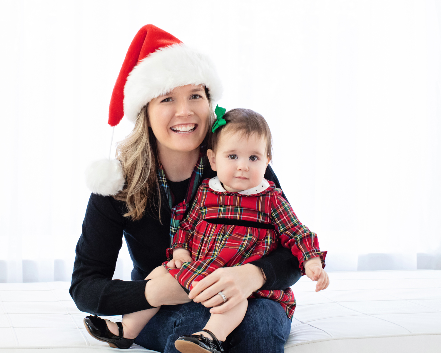 A mom in a Santa hat holds her baby.