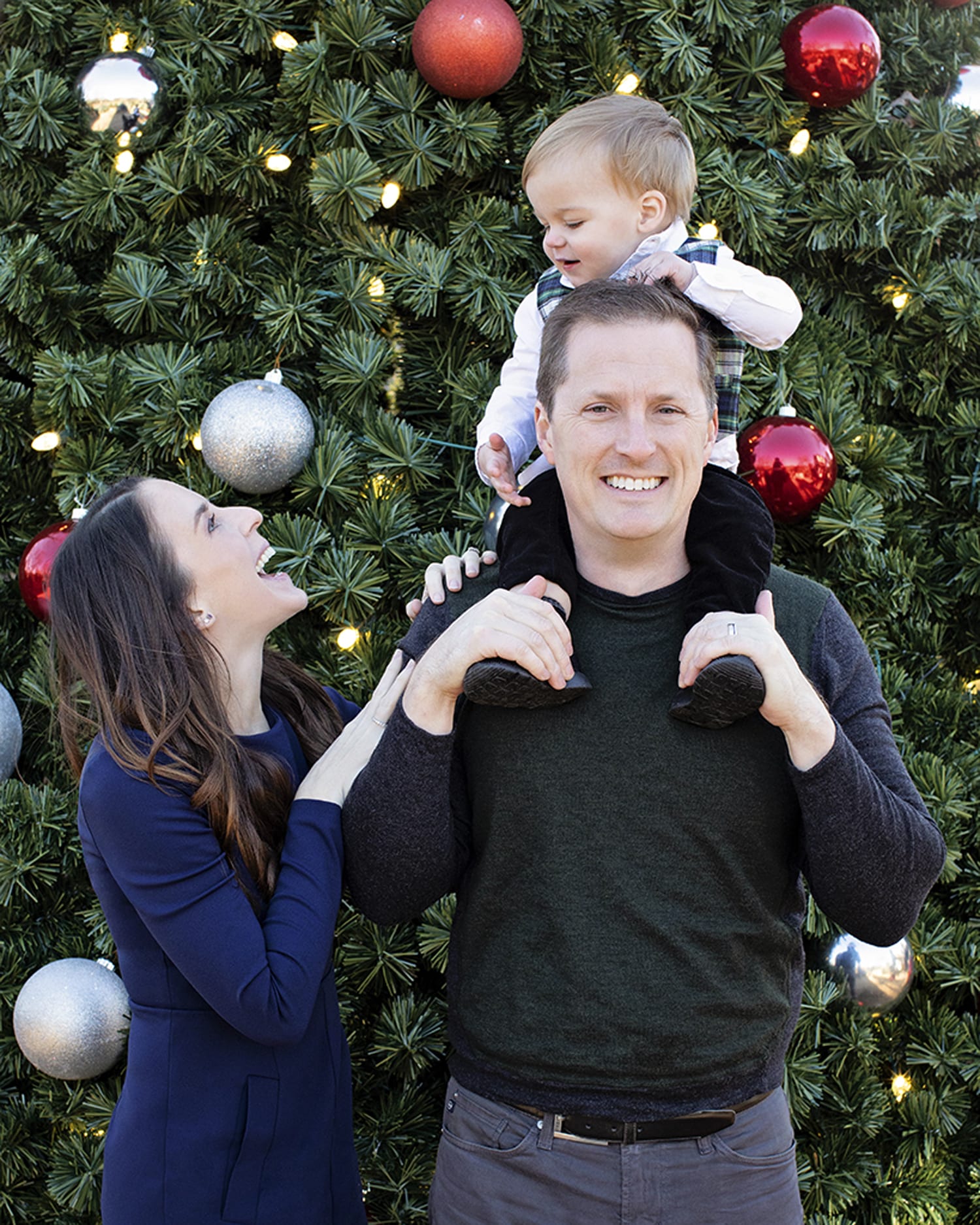 A family takes a photo in front of a Christmas tree.