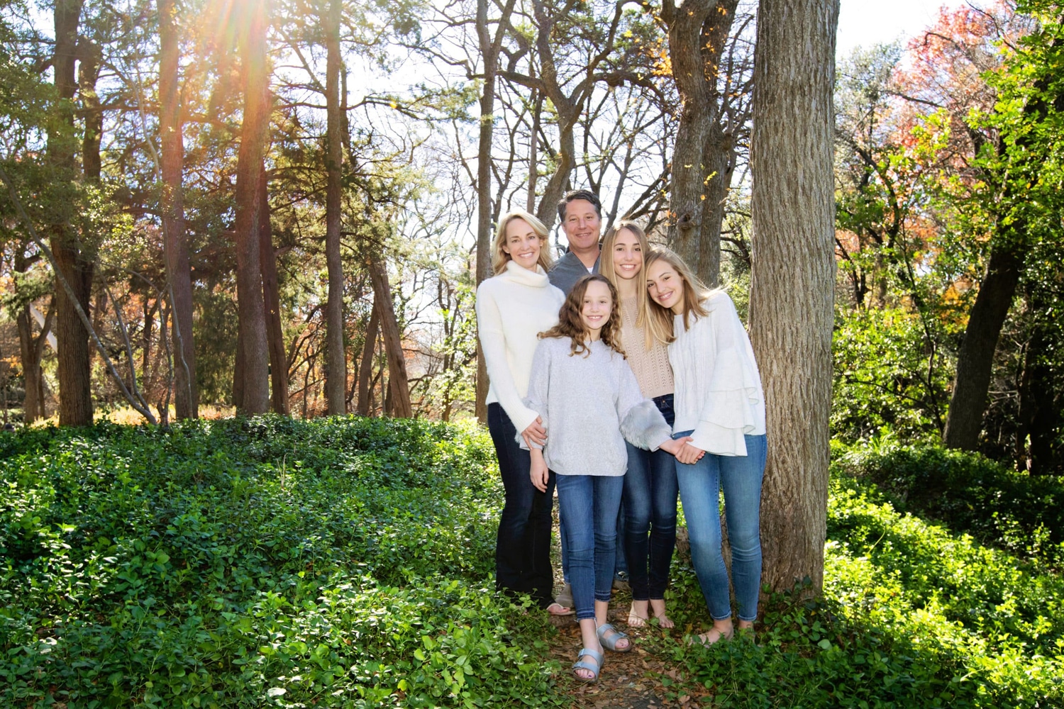 A family of five takes photos outside.