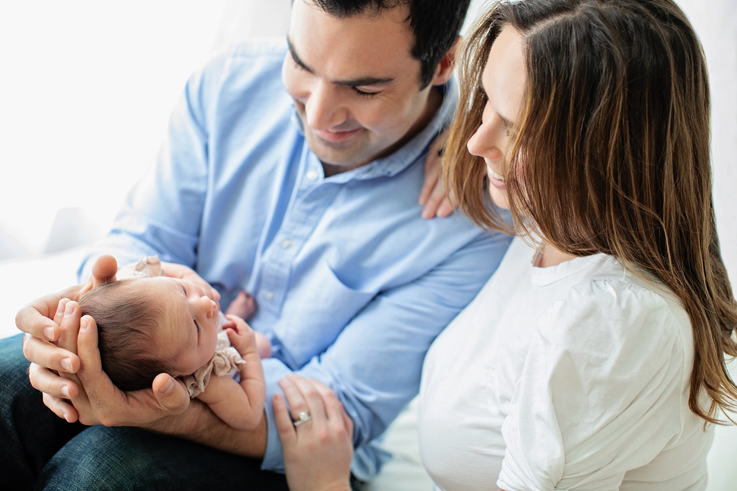 Unique family portrait parents hold baby by window