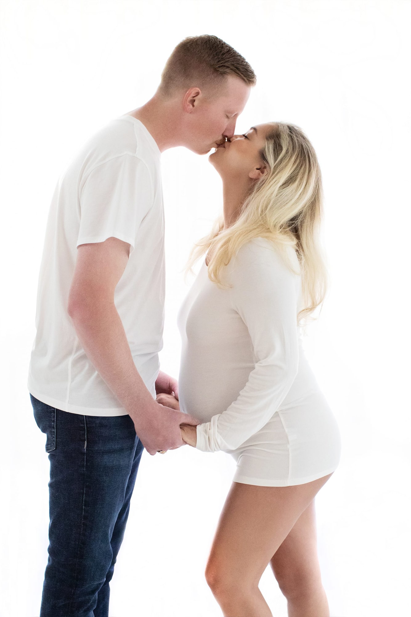 A pregnant woman and her husband kiss.