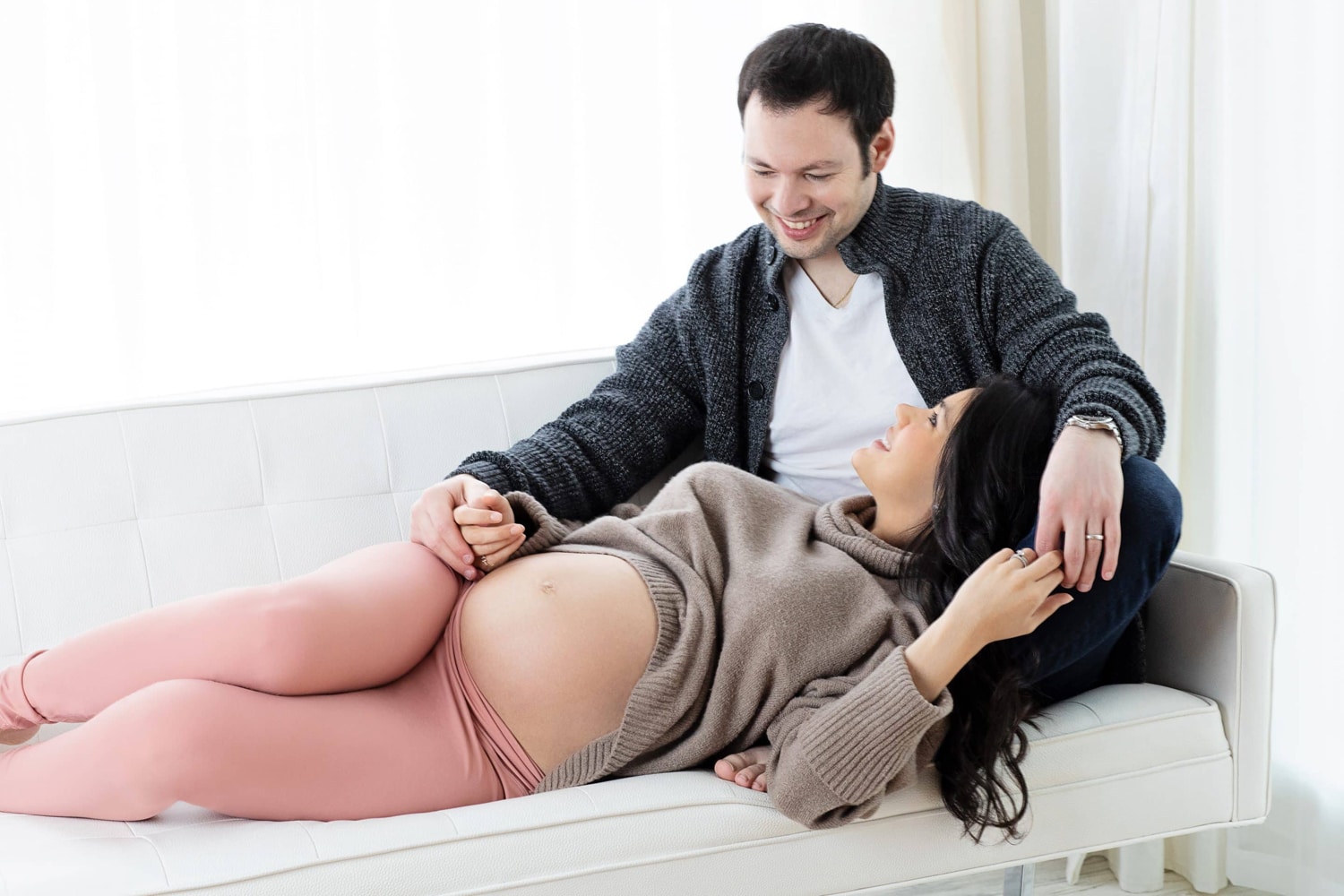 A woman smiles up at her husband for a maternity portrait.