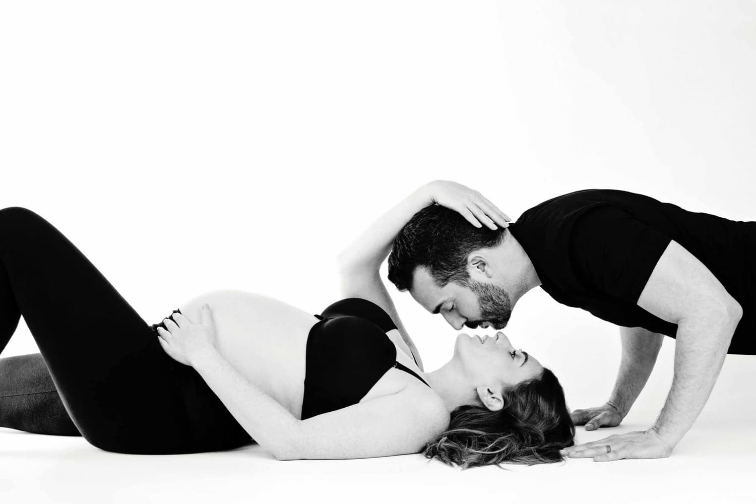 A man kisses his wife for a maternity protrait.