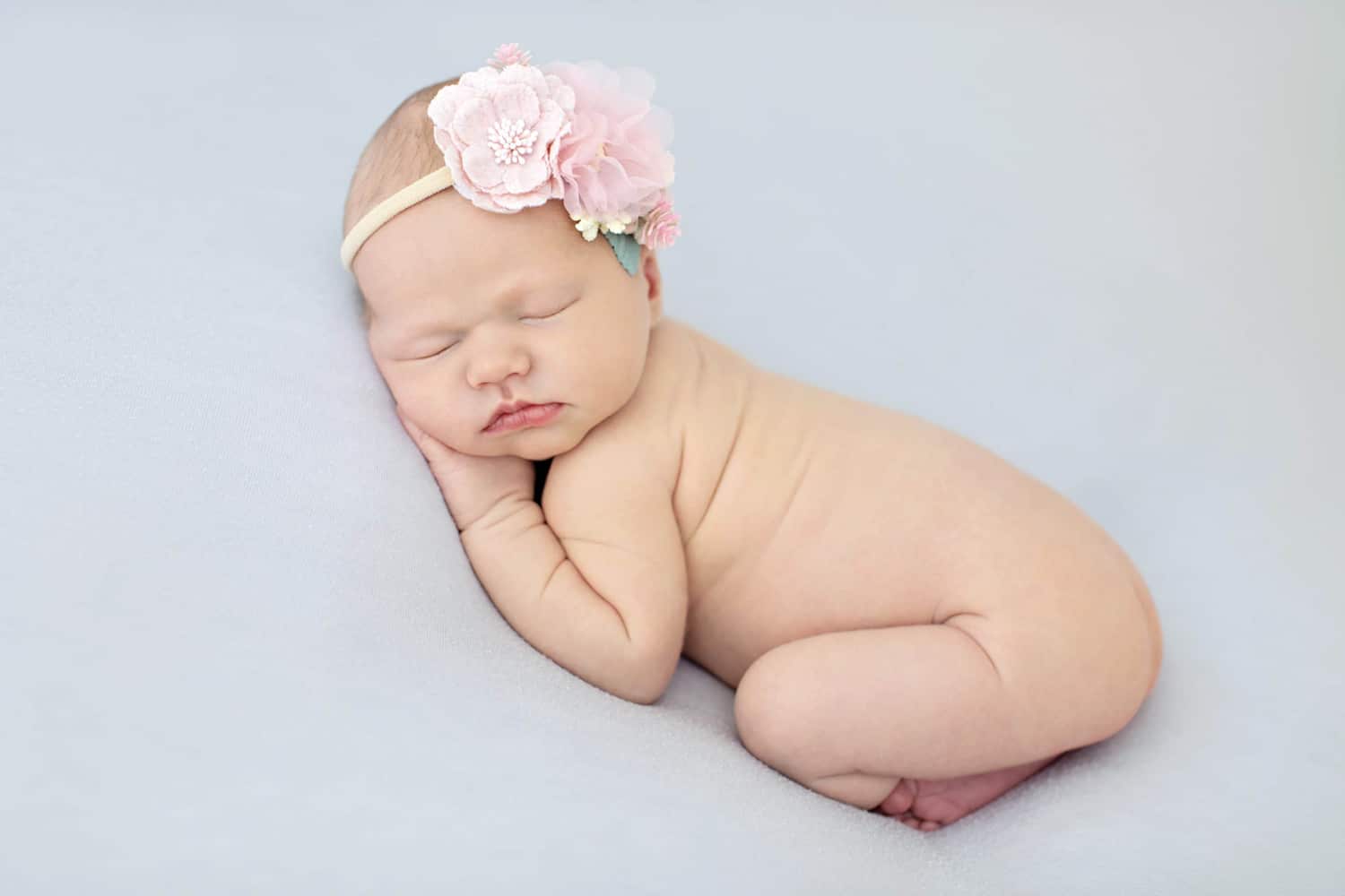 A newborn baby with a flower headband.