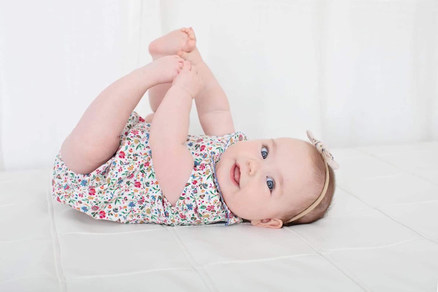 A baby grabs her feet in a minimalist newborn photo.