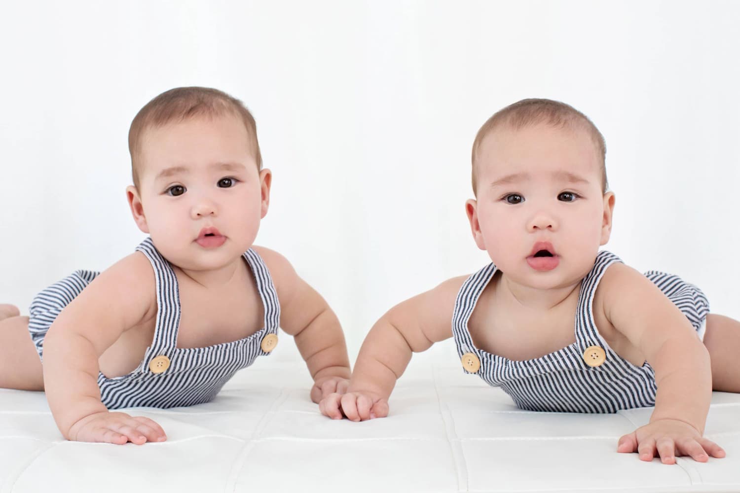 Two newborn babies in matching onesies.
