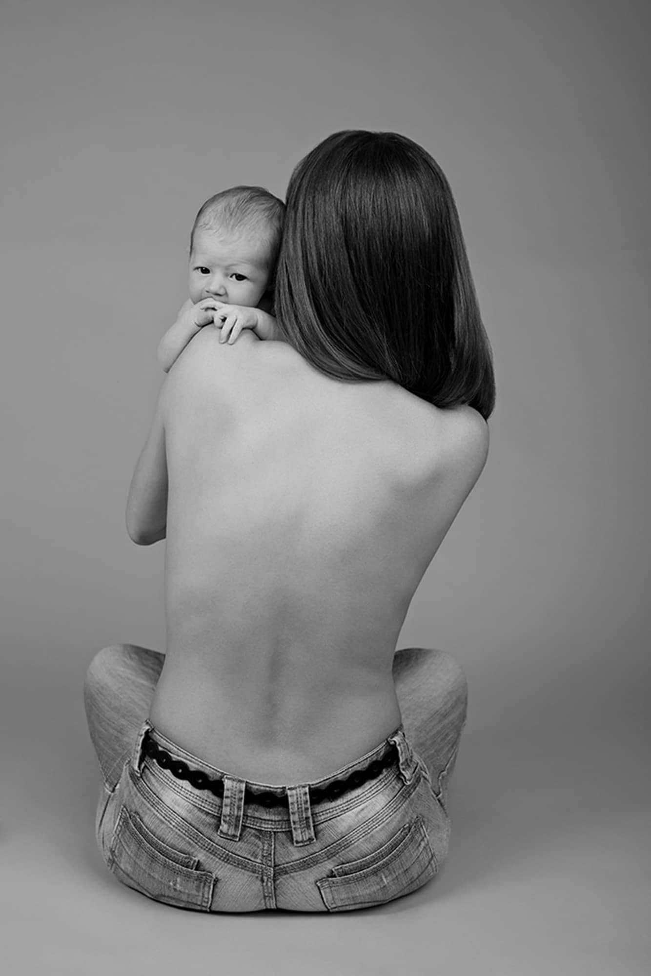 A woman holds her newborn baby over her shoulder.