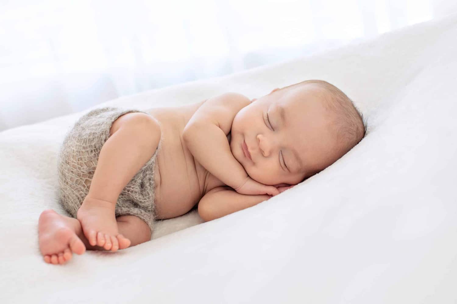 A photo of a newborn baby in gray shorts.