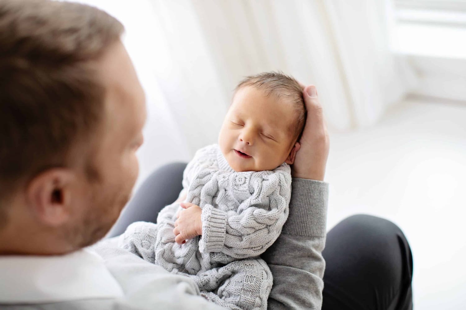 A newborn baby lays in Dad's arms.