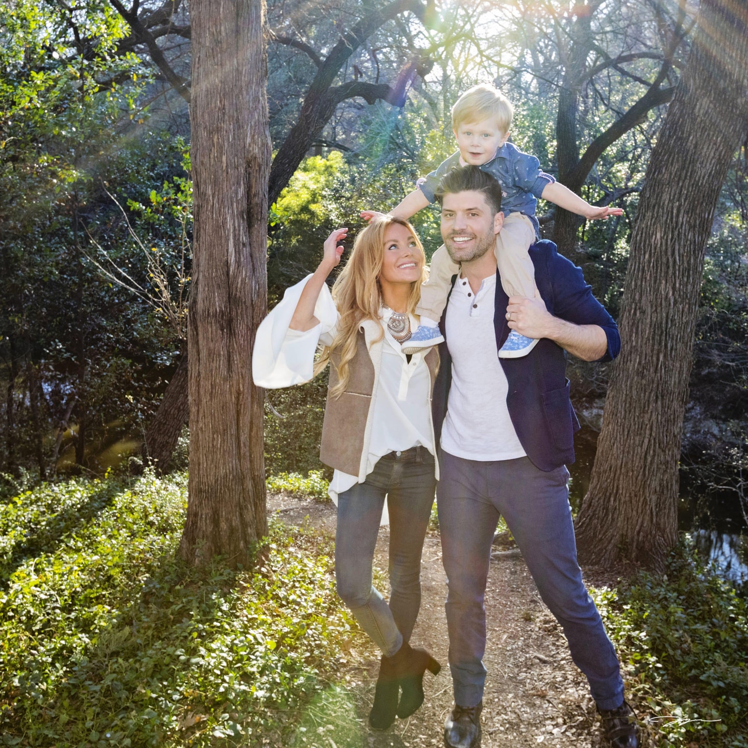 A family take a photo outside in the trees.