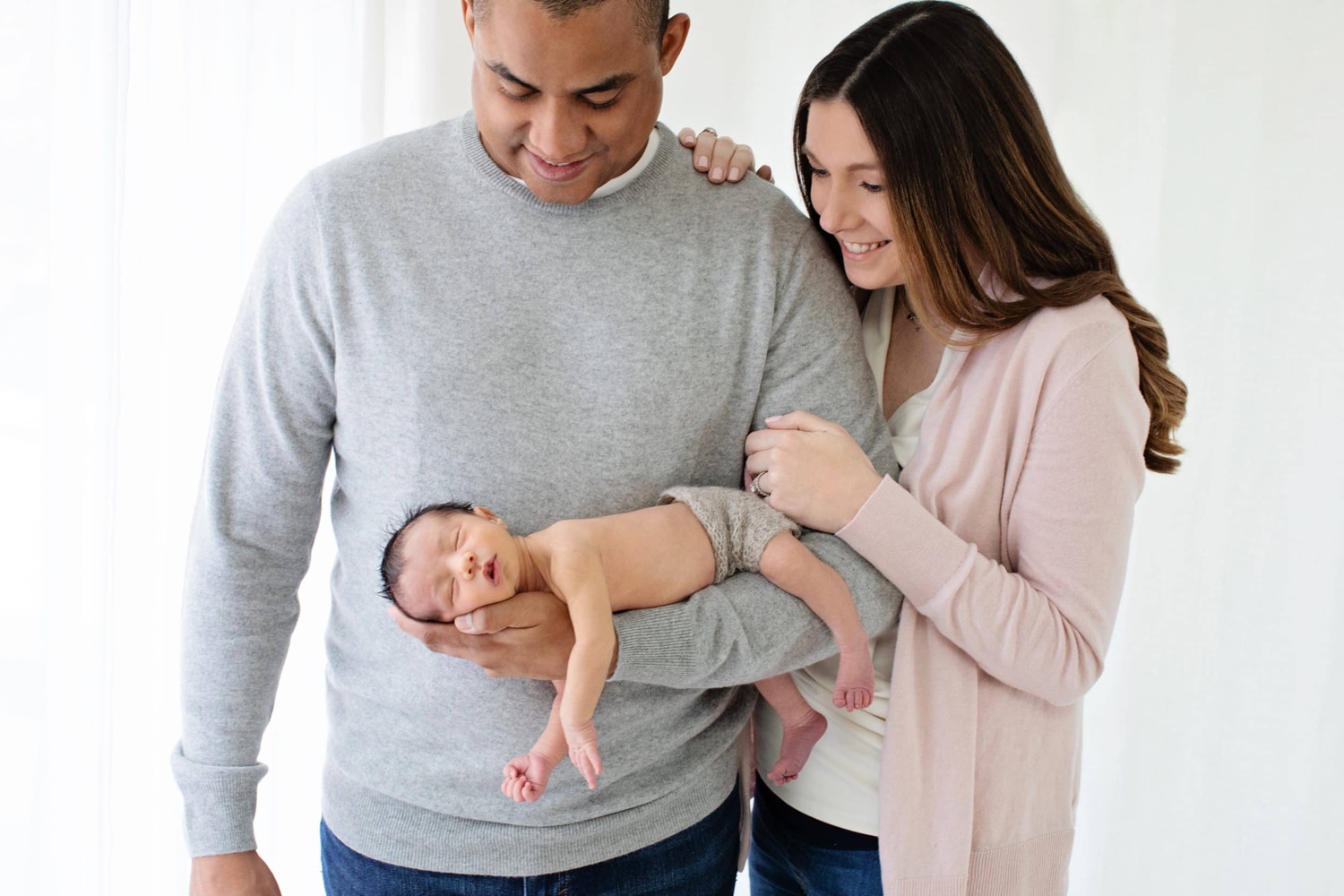 Two parents and their baby take a family photo.