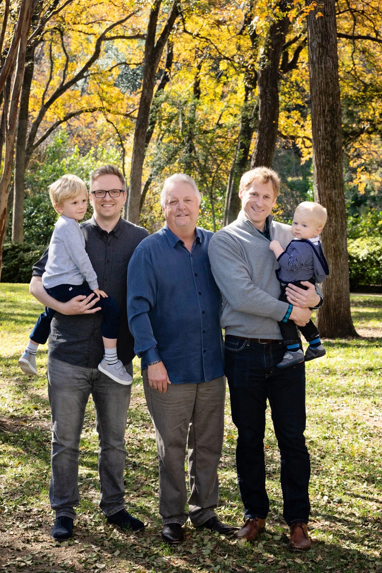 A family takes a photo outside in the trees.