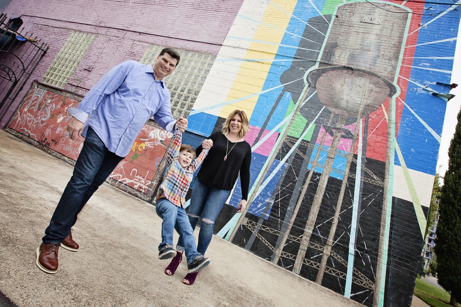 A family takes a photo in front of a mural.