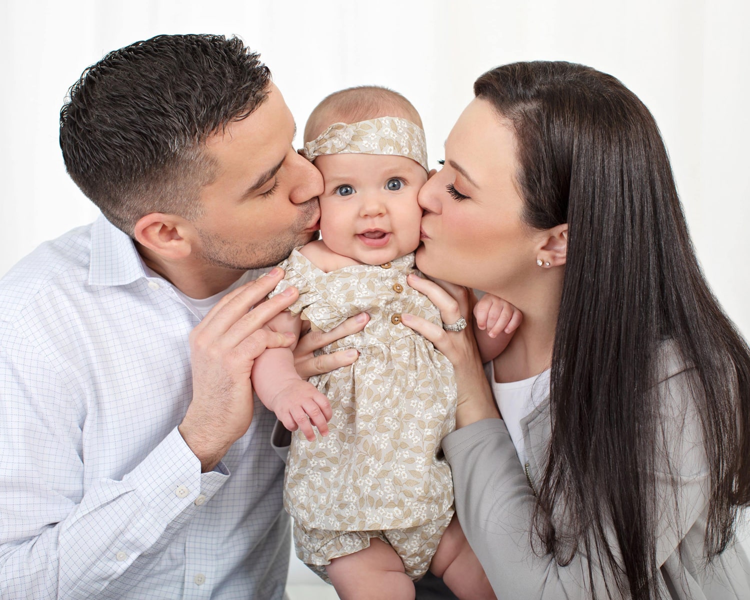 Two parents and their baby take a family photo.