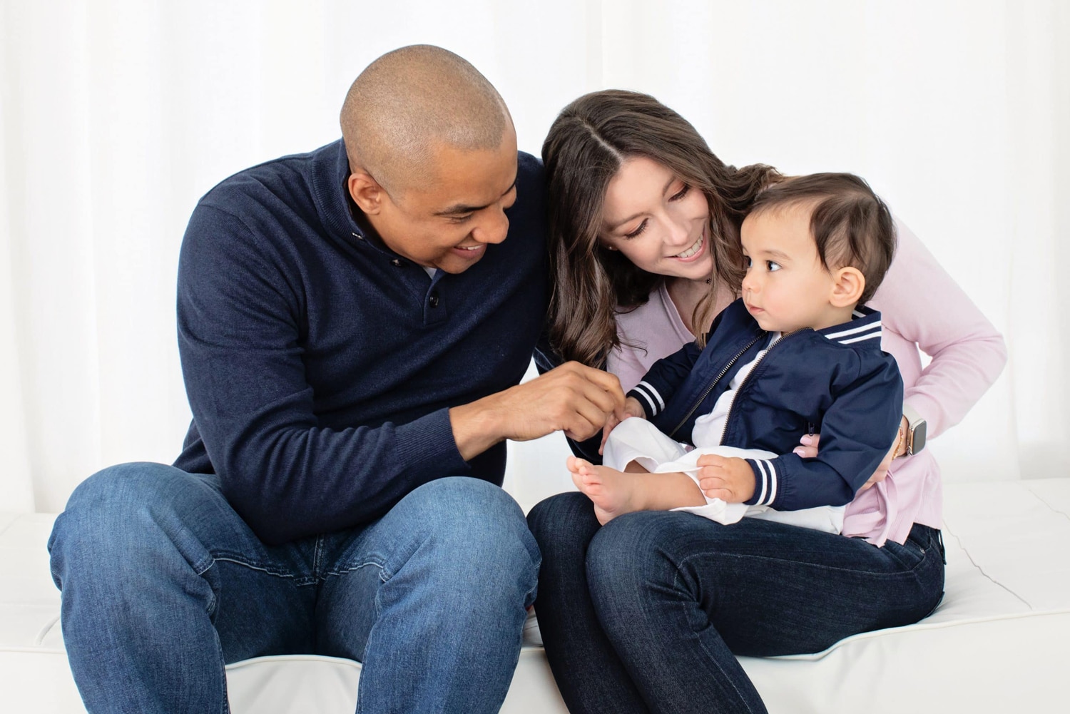 Two parents and their child take a family photo.