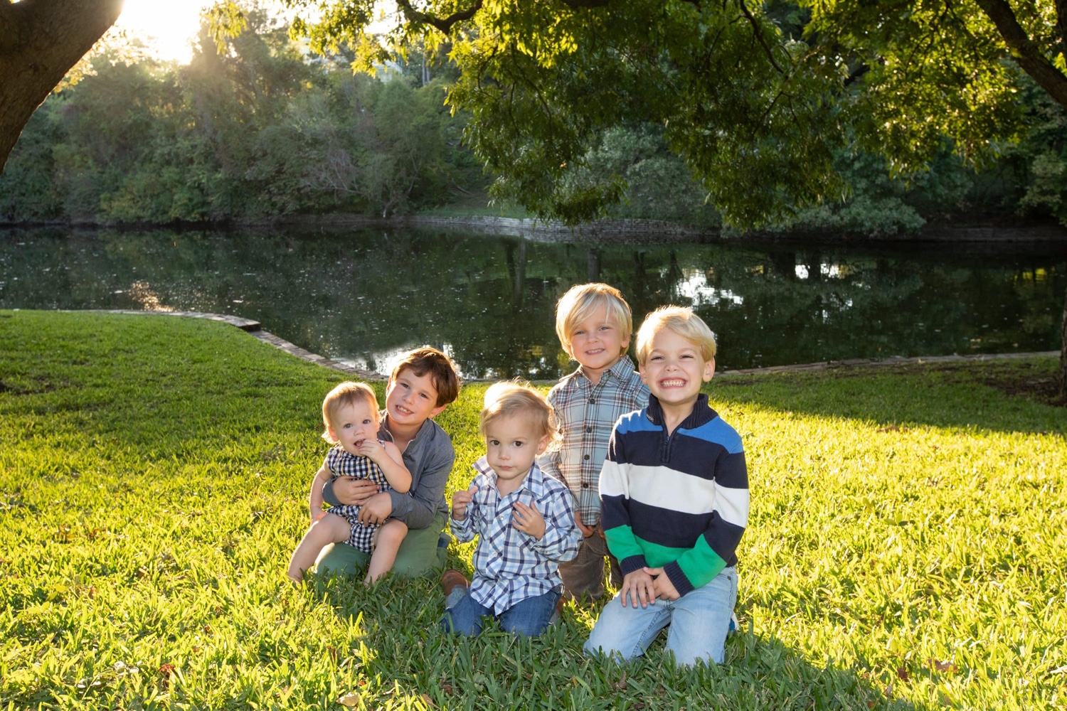 A group of siblings take a photo outside on the grass.