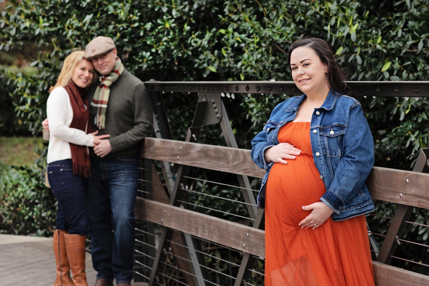 A surrogate mother in a red dress with the two parents.