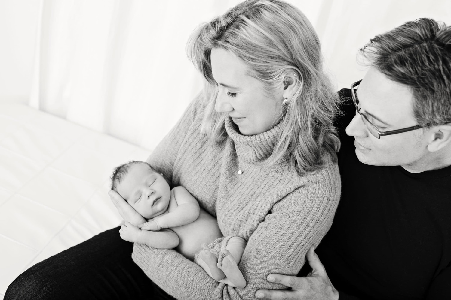 Black & white photo of parents holding their new baby via surrogacy.