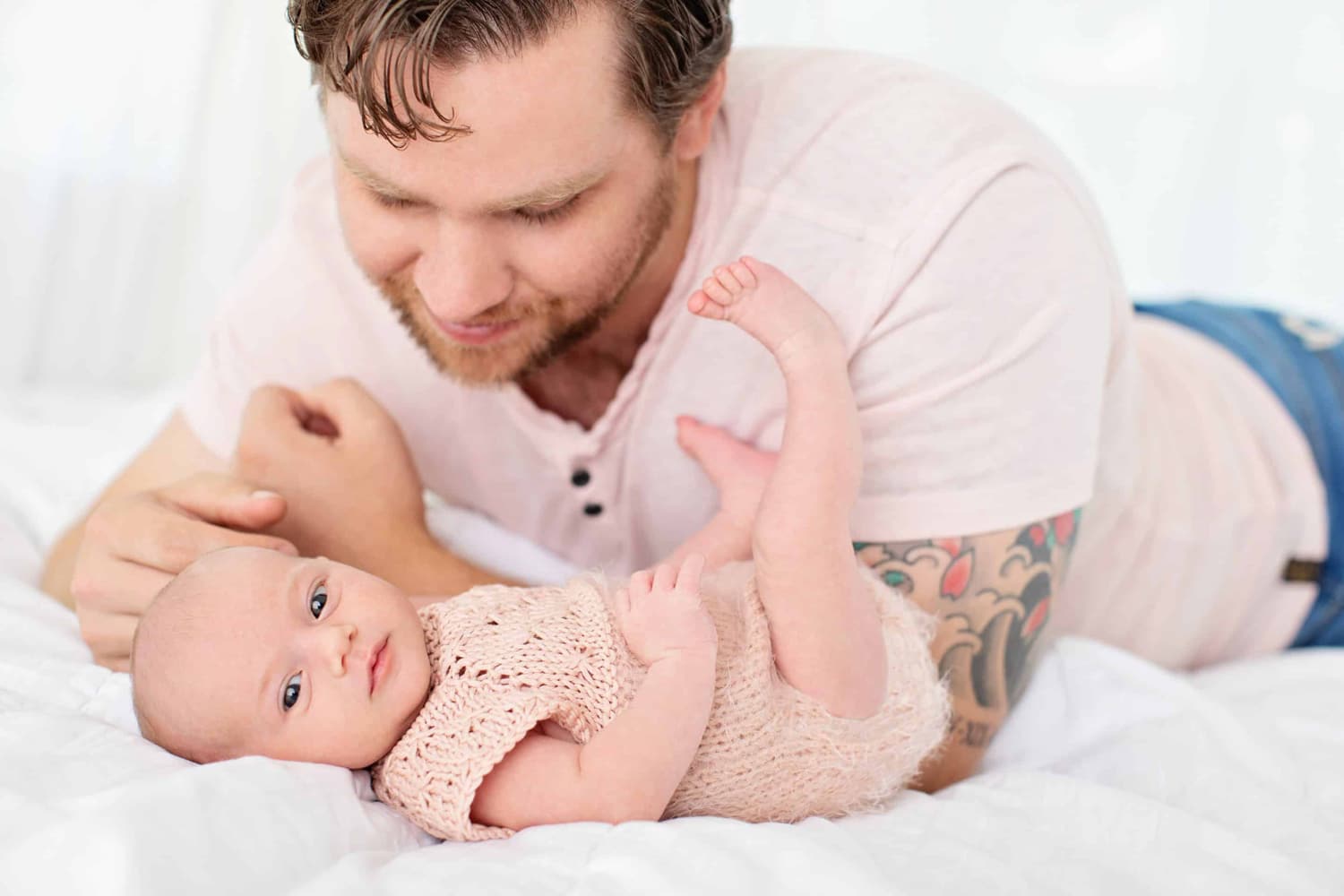 A man looks down at his baby in a knit onesie.