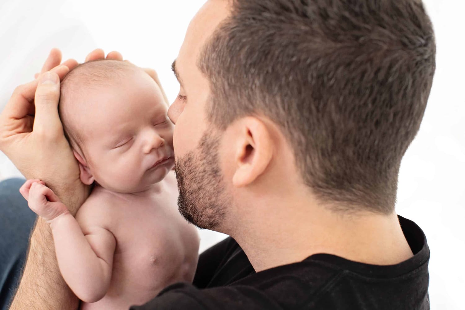 A man cradles his newborn baby's head.