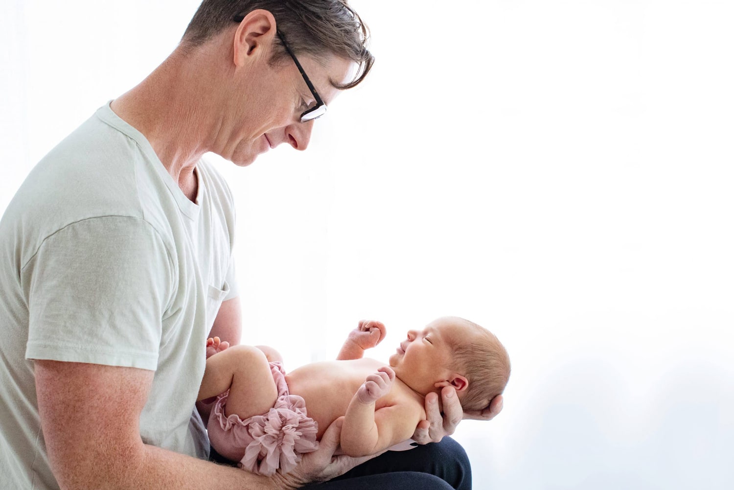 A man cradles his newborn baby.