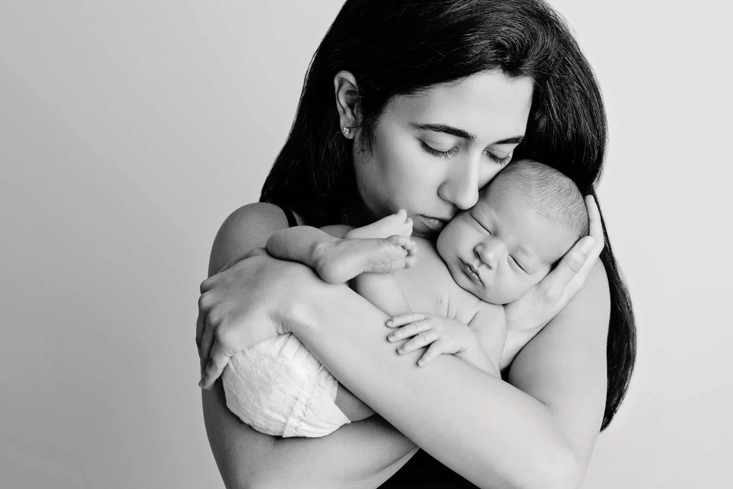 A dark-haired woman cradles her newborn baby.