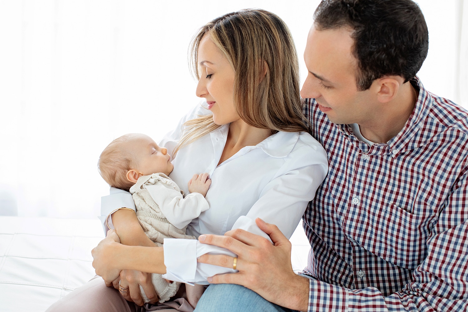 A couple looks at their three month old baby.