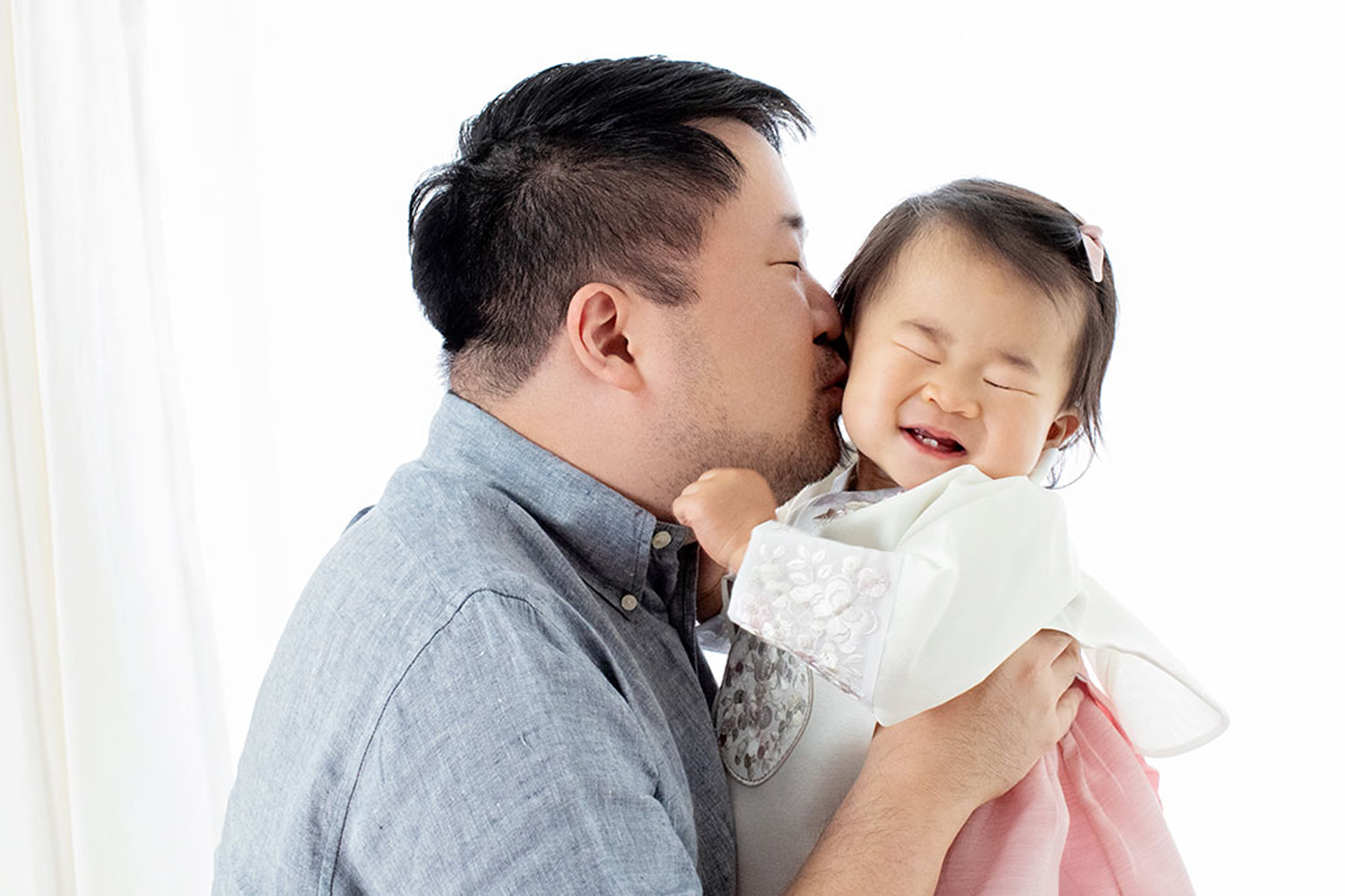 A dad kisses his one-year-old.