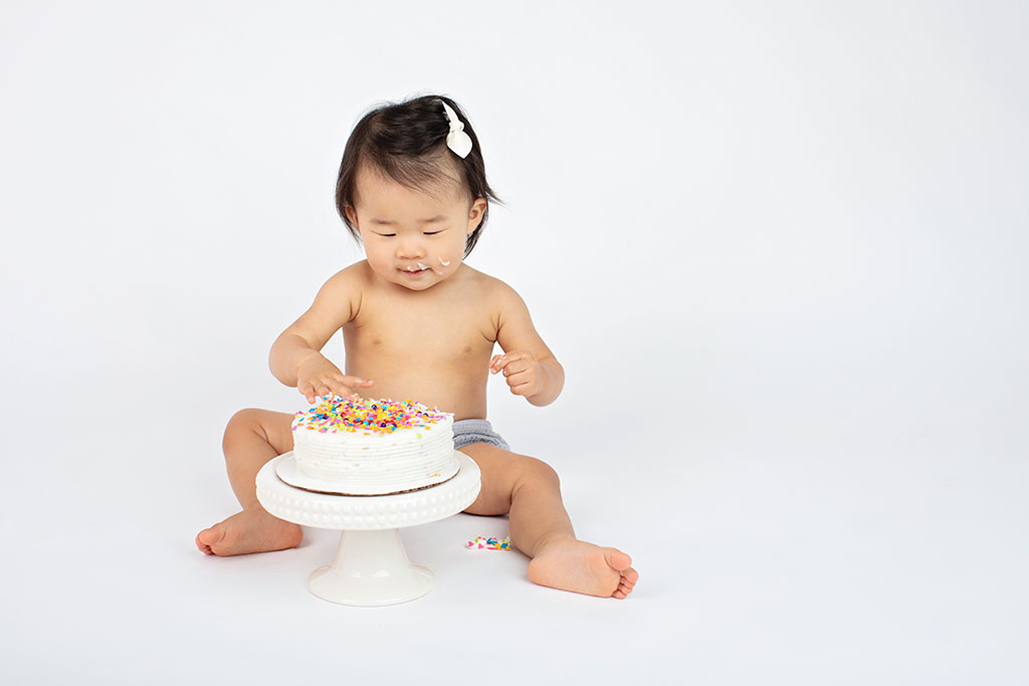 A baby eats their birthday cake.