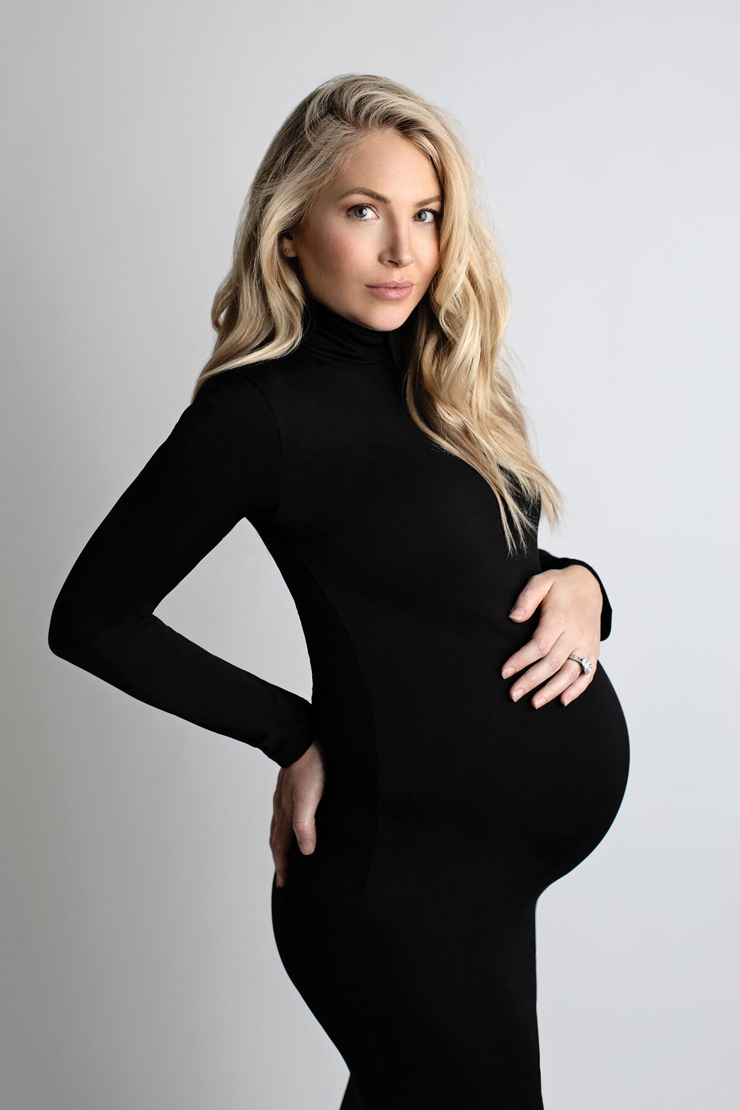 Fine art pregnancy photos of a woman in a black turtleneck dress.