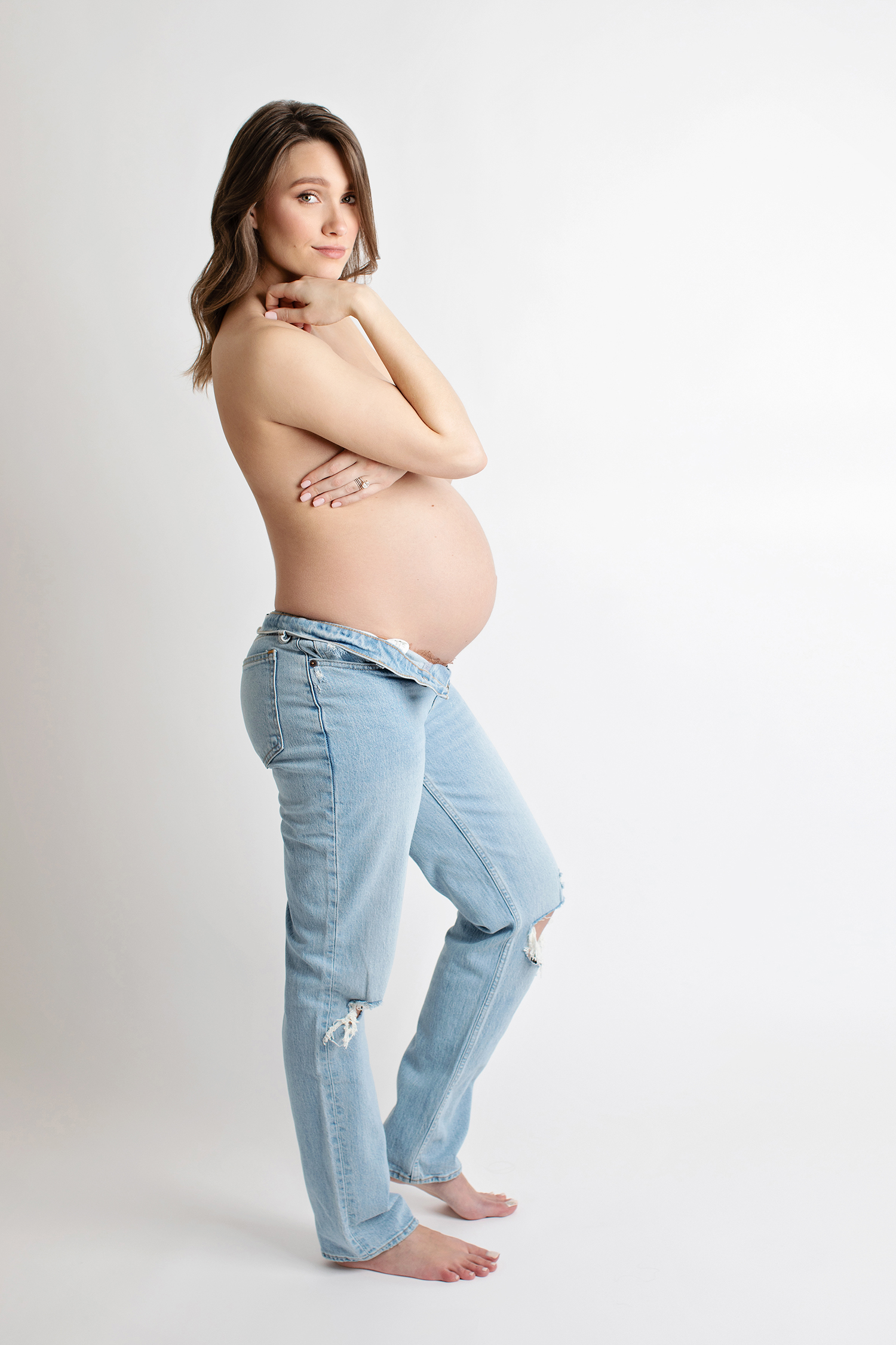 A maternity photo of a woman in jeans.