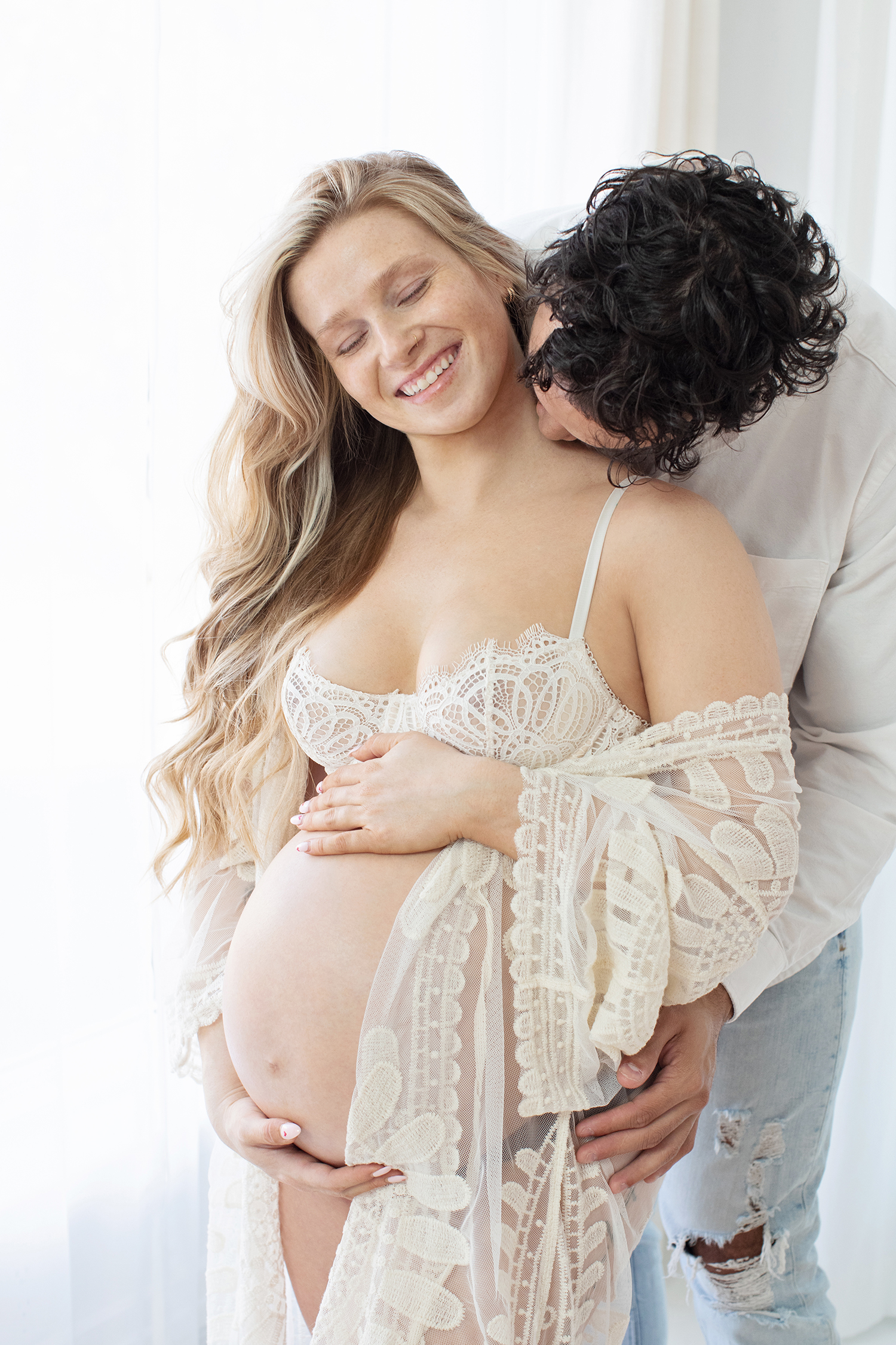 A pregnant woman cuddles with her husband.