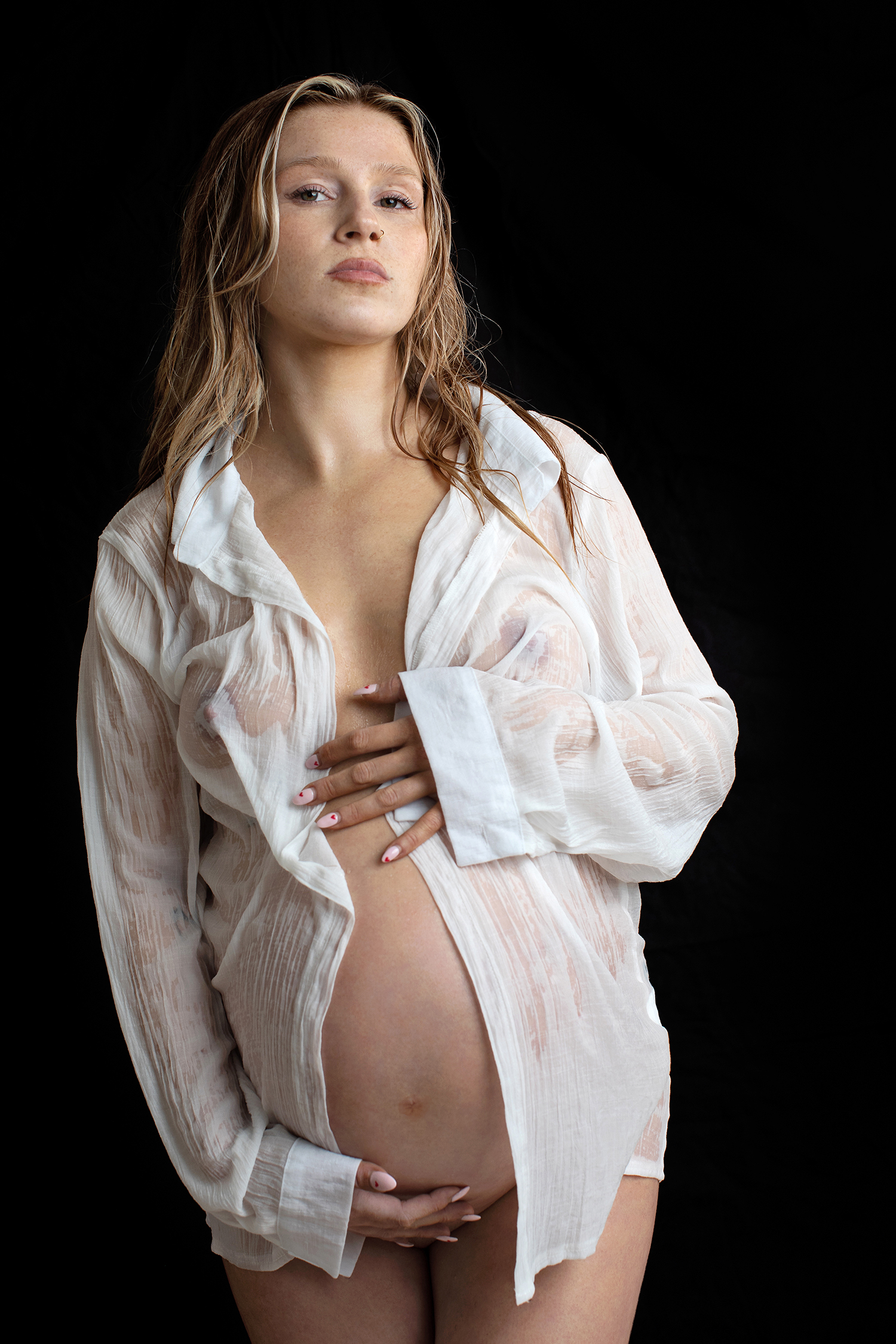 High fashion maternity photo of a woman in a white top.