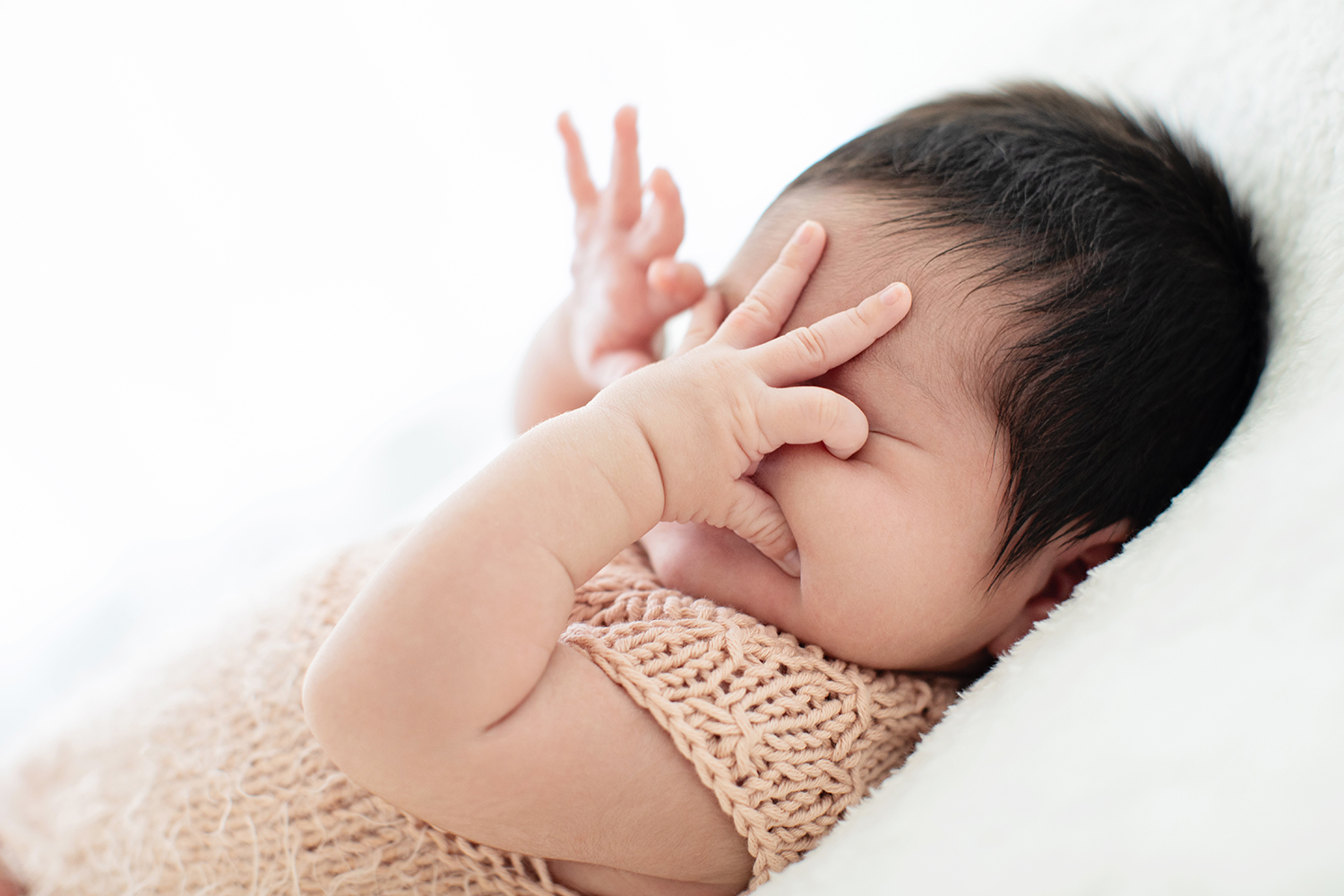 A newborn touches their face.