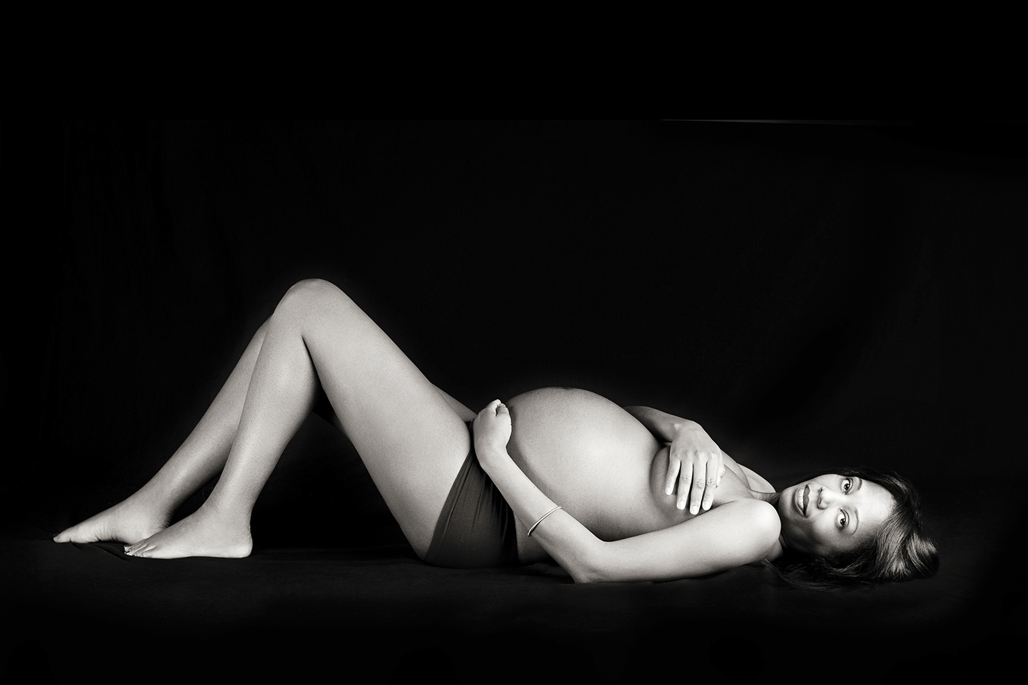 A classic black and white image of a pregnant woman, emphasizing the simplicity and natural beauty.