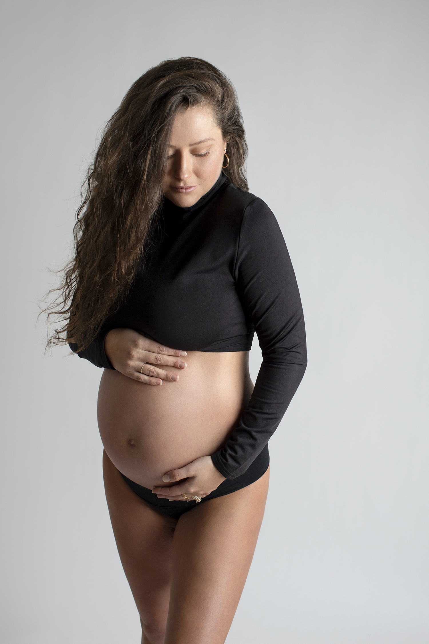 An elegant pregnant woman is captured in a luxury maternity photoshoot, exuding confidence and beauty.