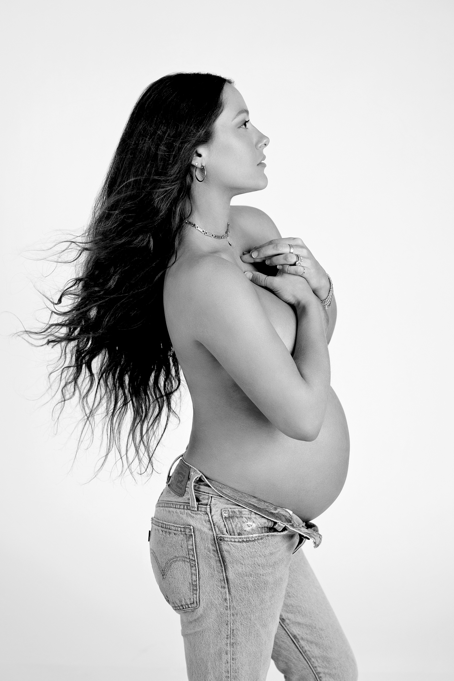 A timeless black and white maternity photo, featuring a mom-to-be cradling her heart and looking towards the future with anticipation