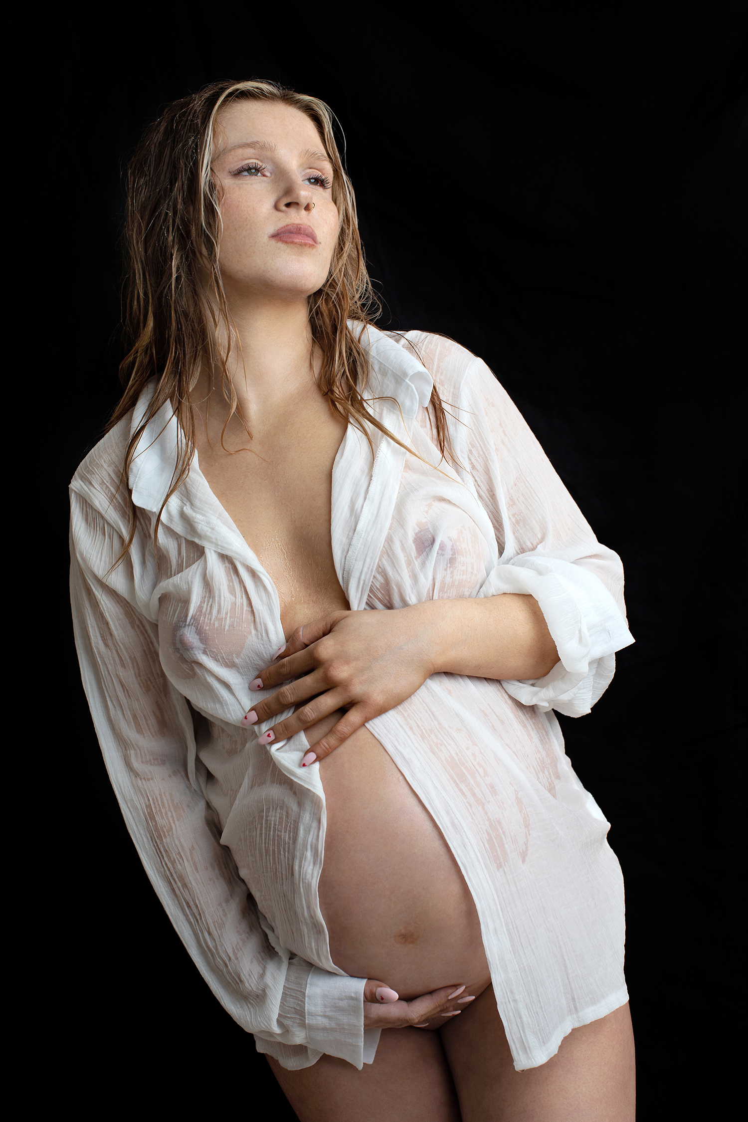A pensive pregnant woman is capturedin a luxury maternity photoshoot, exuding confidence and beauty.
