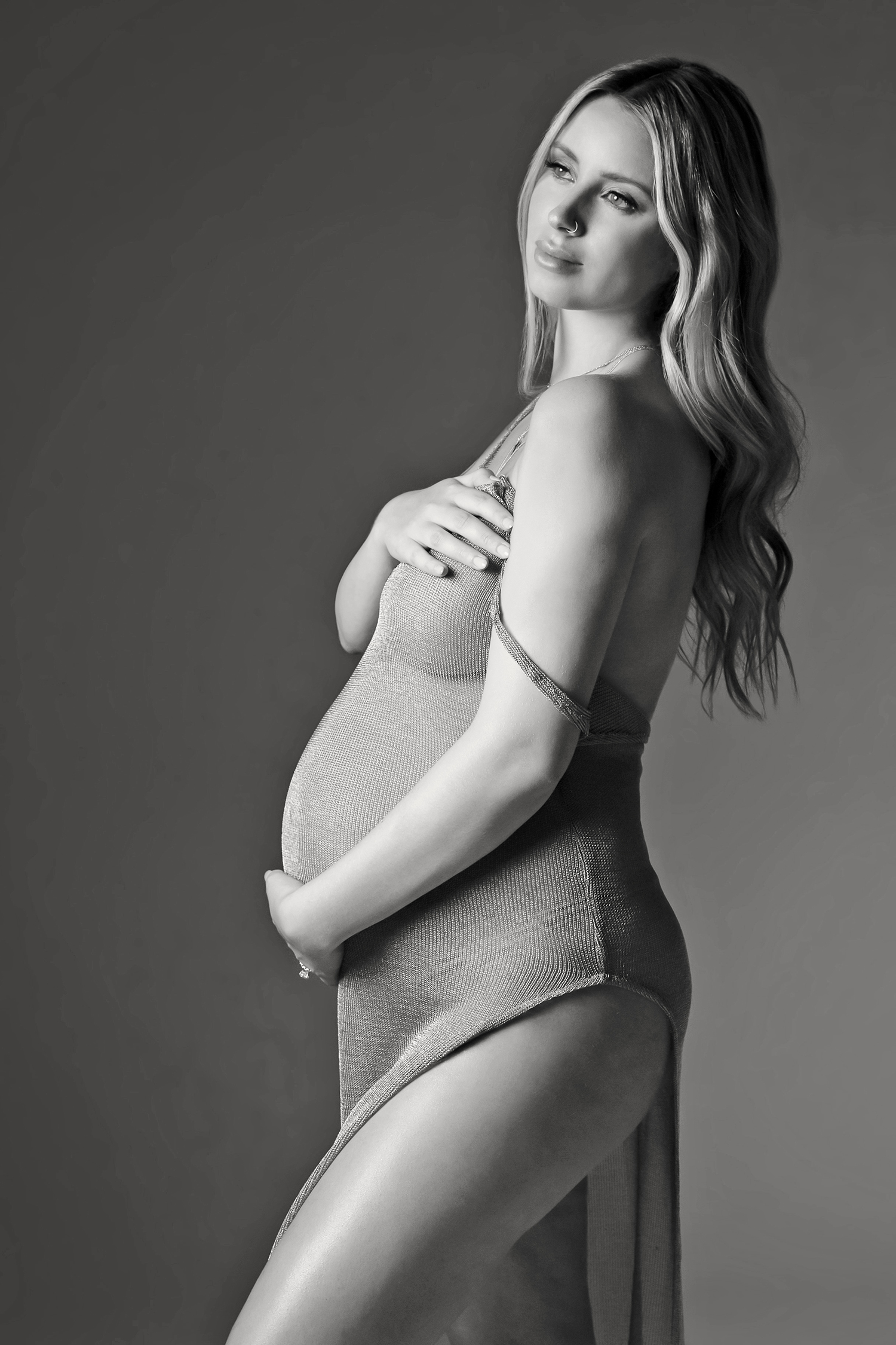 Delicate fabrics create a serene atmosphere as a pregnant womanposes serenely during her luxury maternity photoshoot.