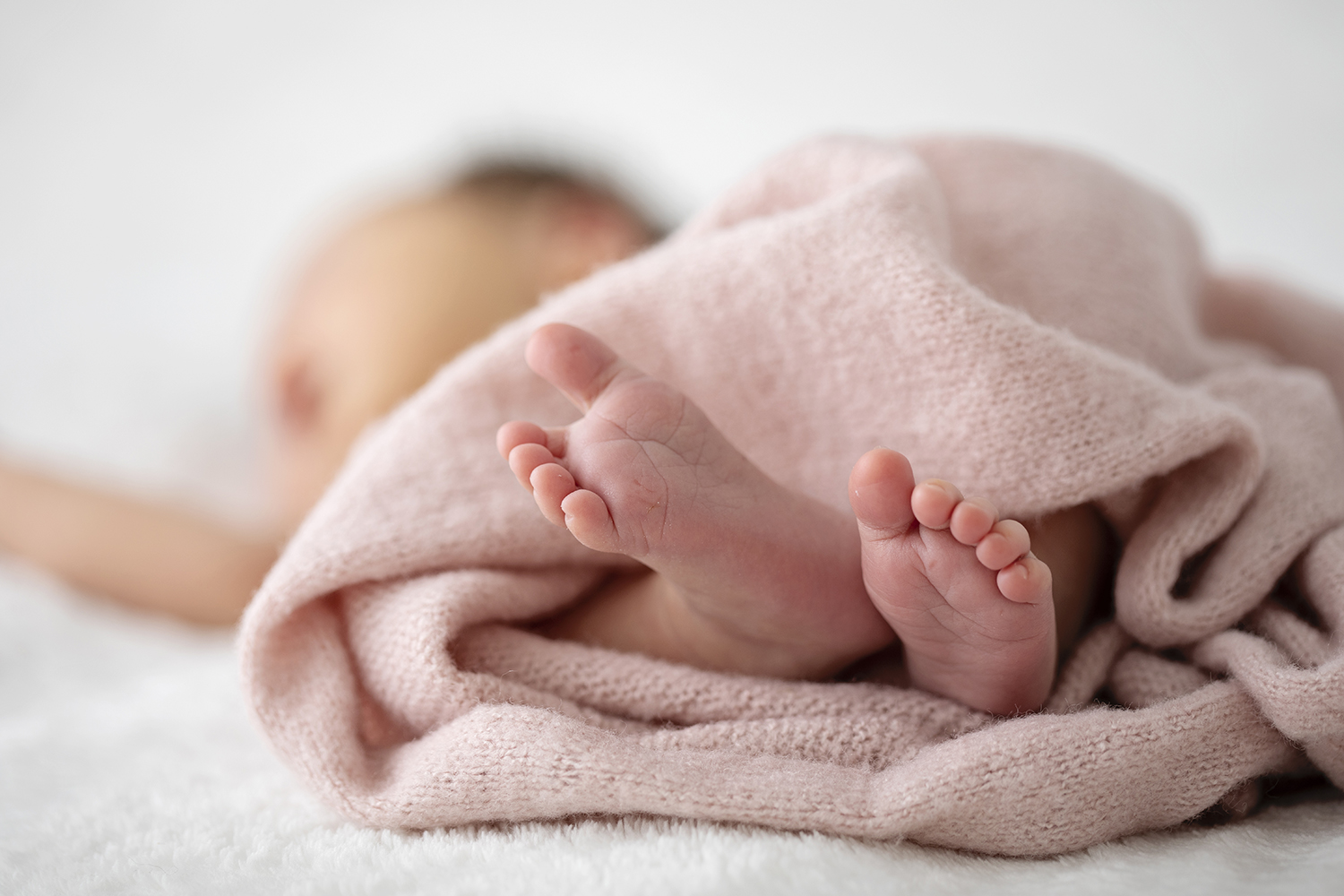 A close-up photograph of the toes and feet of a newborn baby