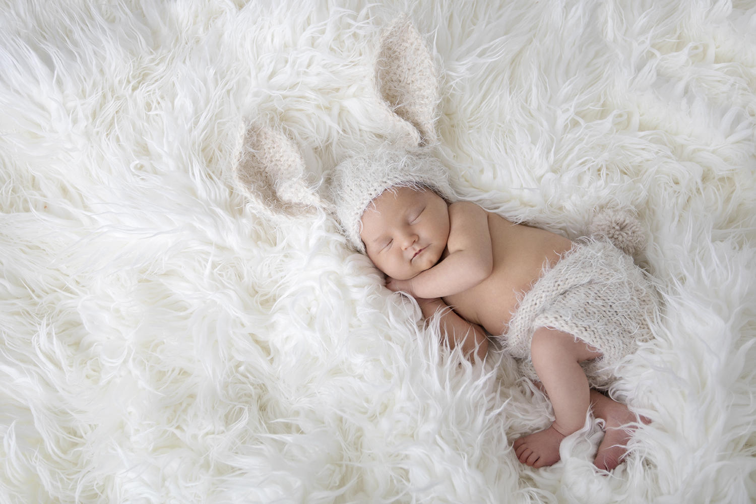 A photograph showcasing the delicate features of a newborn baby, with bunny ears and closed eyes, radiating innocence and serenity.