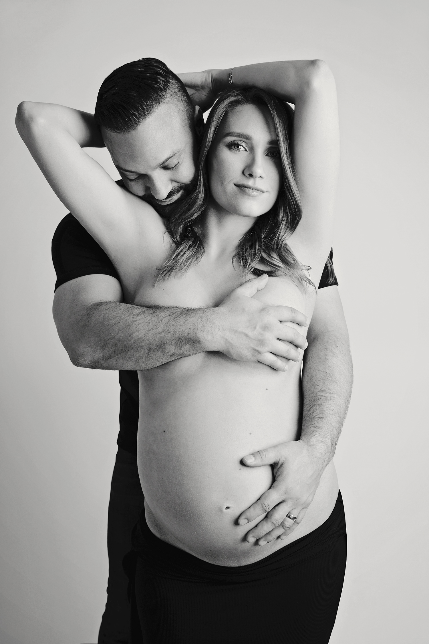 a man and a pregnant woman embrace each other in a black and white photo
