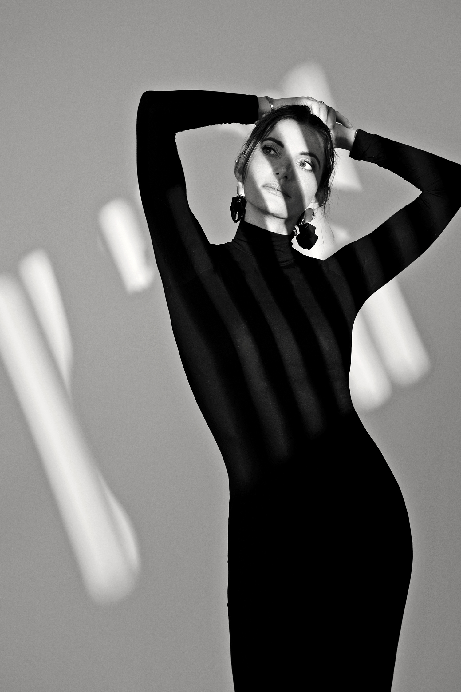 black and white fashion image of woman in black dress and dramatic lighting