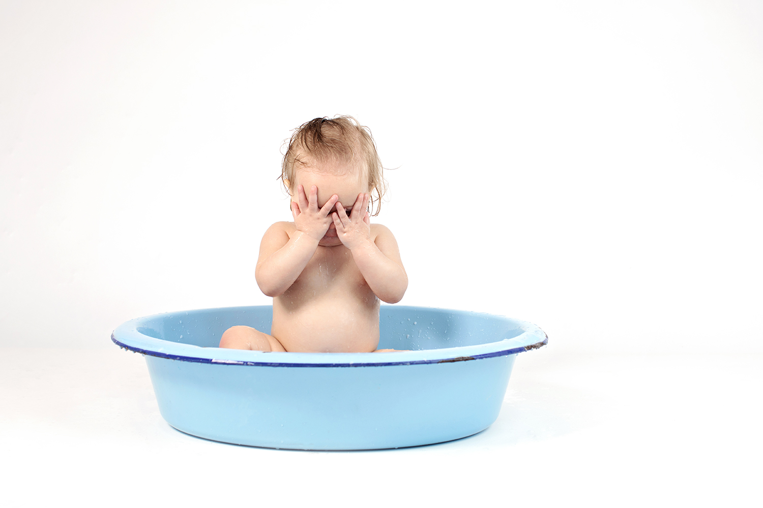 a cute baby acting shy in a vintage tin tub