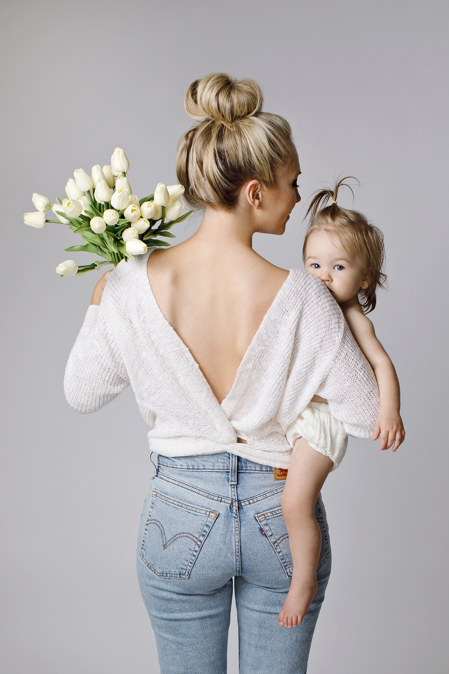 a mother from the back holding flowers and her baby